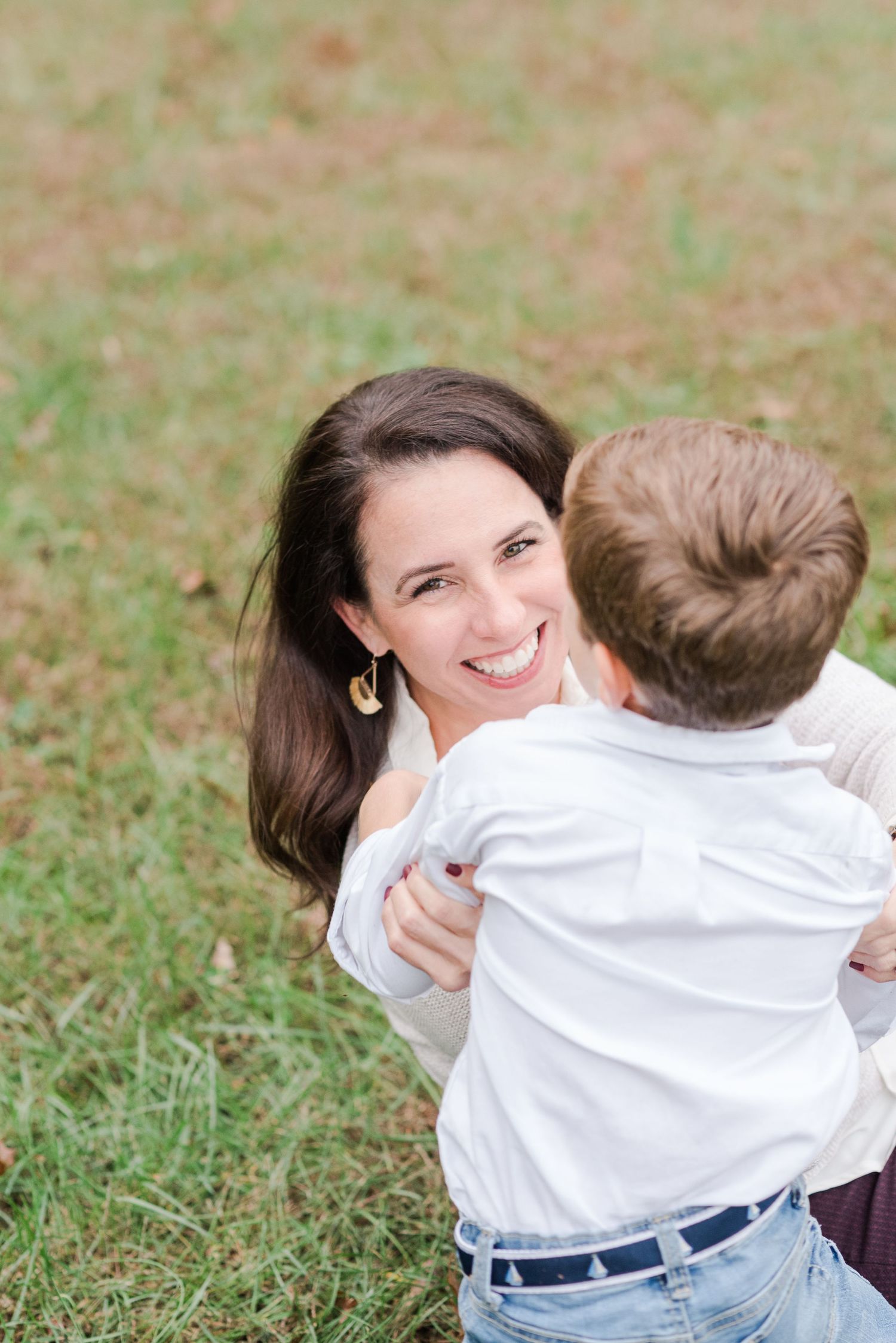 Candid outdoor family moment capturing joyful interaction in a grassy setting.