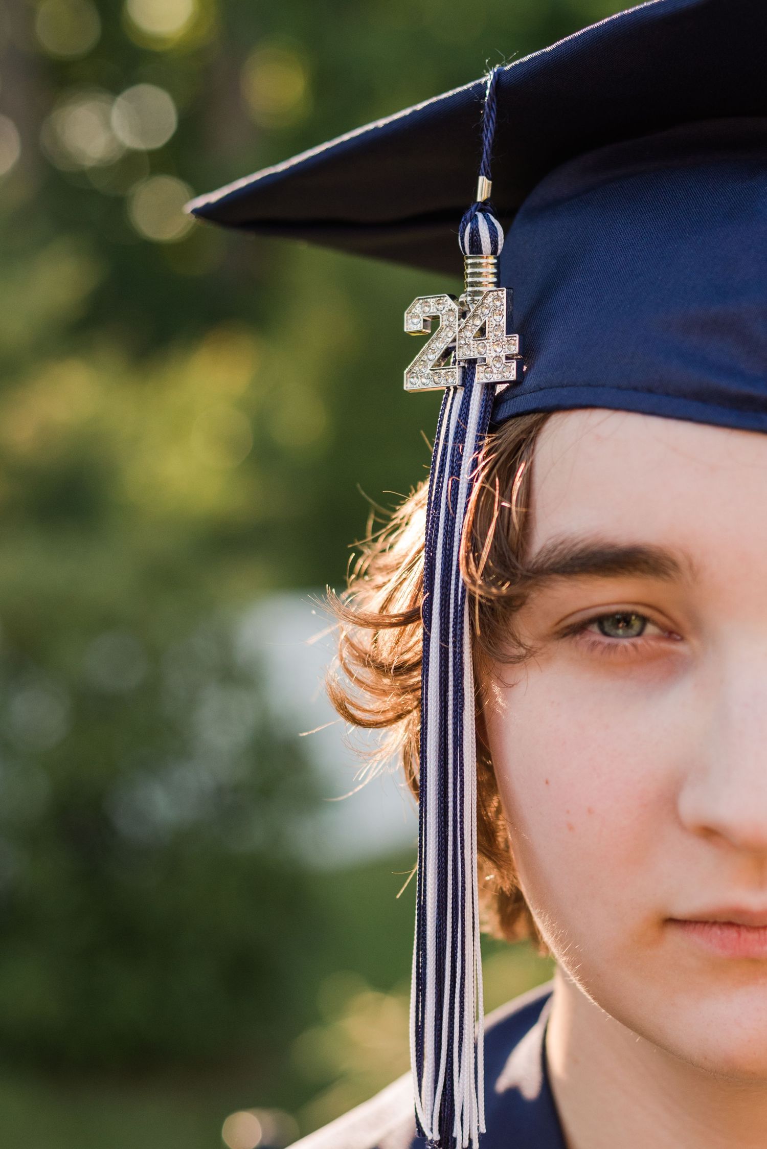 A graduation cap with 2021 tassel charm photographed against a blurred green natural background.