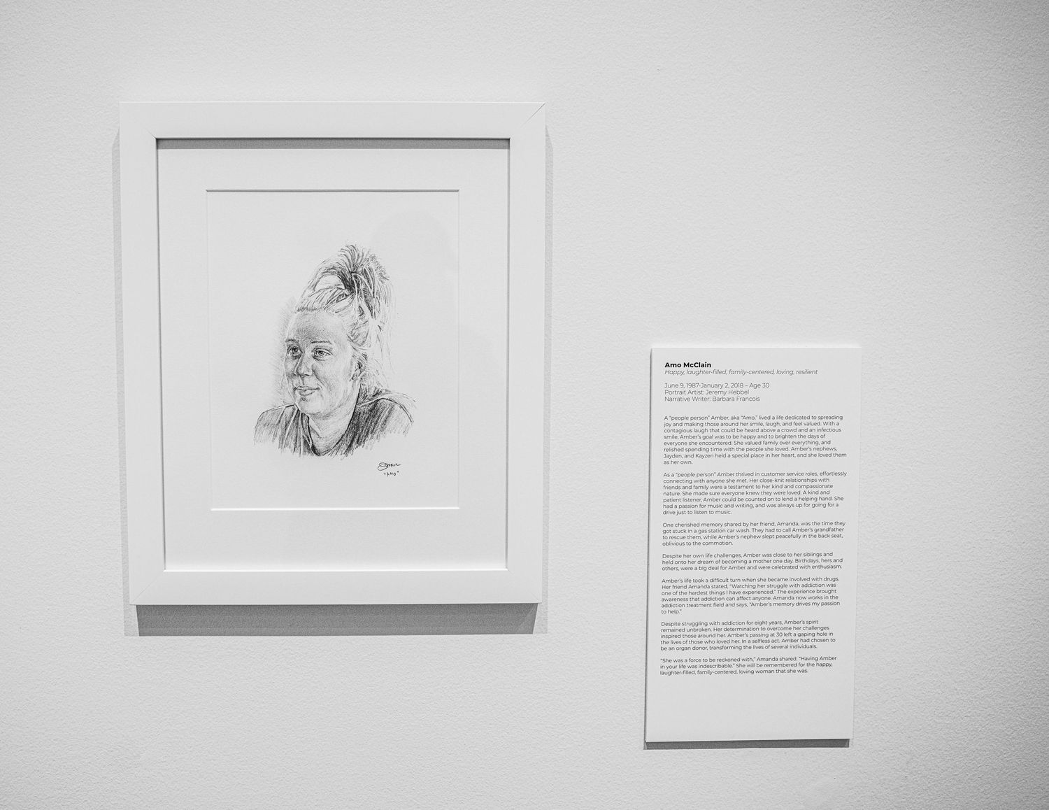 Art gallery wall showing framed pencil sketches and accompanying narrative text panels.