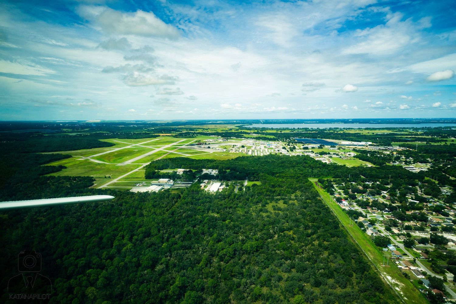 Expansive aerial landscape showing urban development transitioning into green suburban areas.