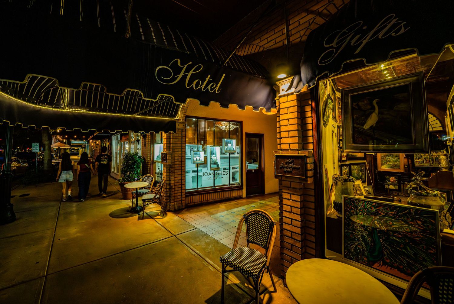Nighttime view of illuminated storefront with vintage architectural details.
