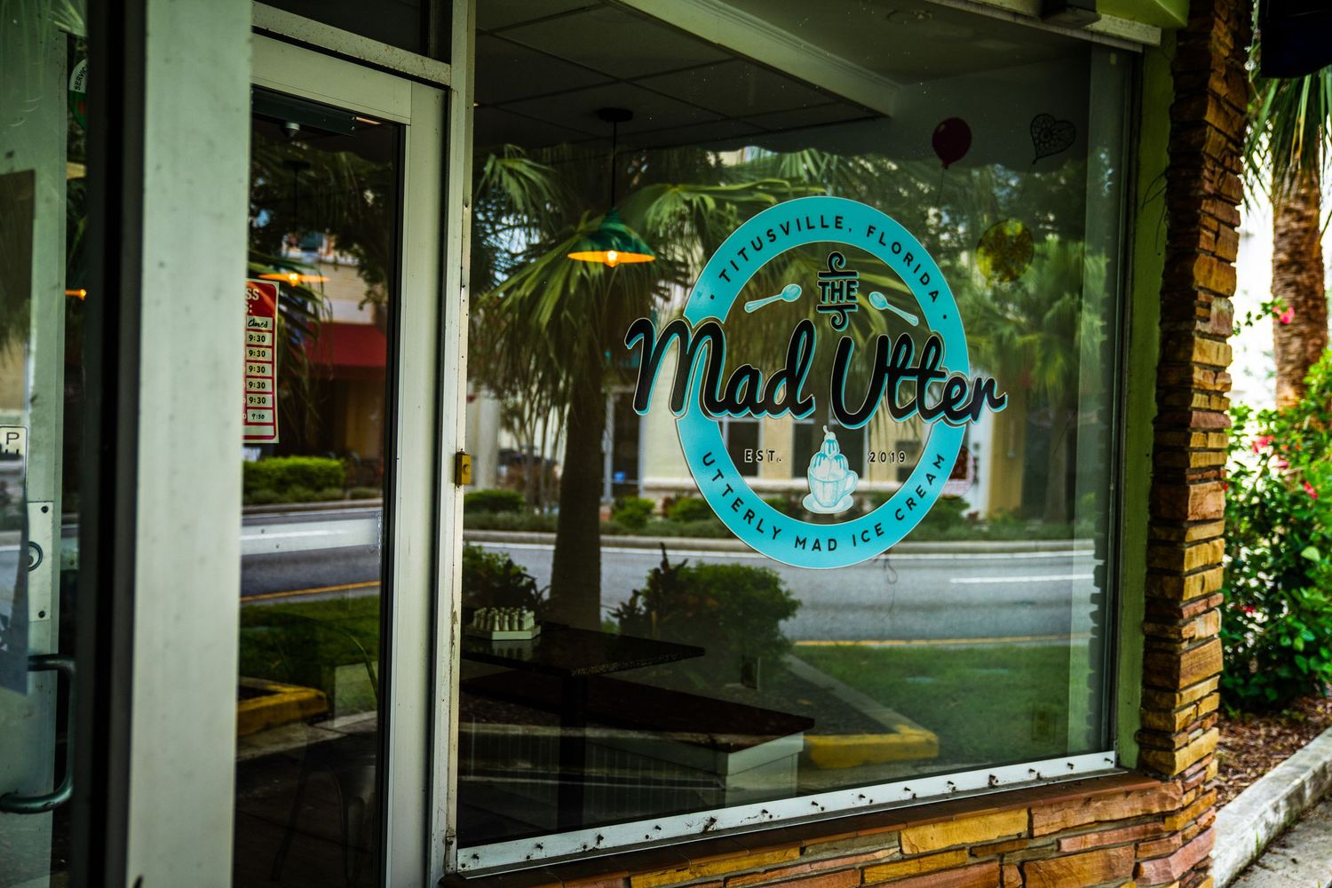 Storefront window display with turquoise signage and reflective glass.