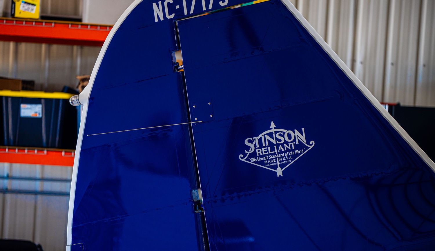 Registration numbers and Stinson branding visible on blue aircraft fuselage.