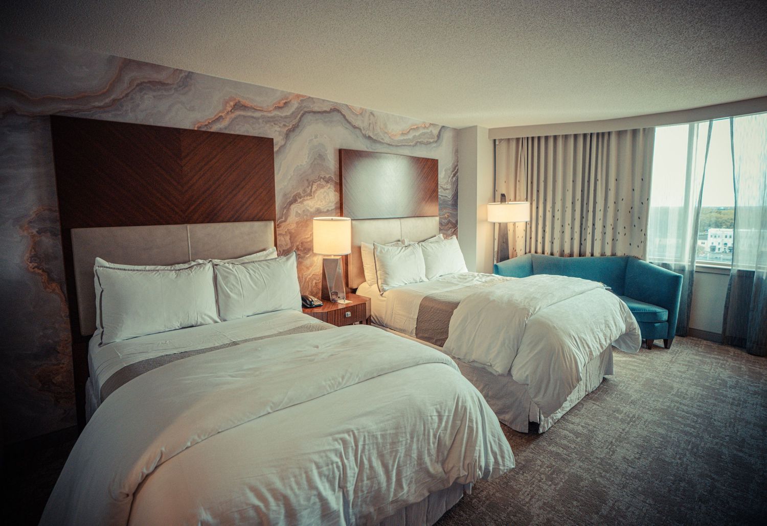 Luxurious hotel room interior with crisp white bedding, modern furnishings, and soft ambient lighting.