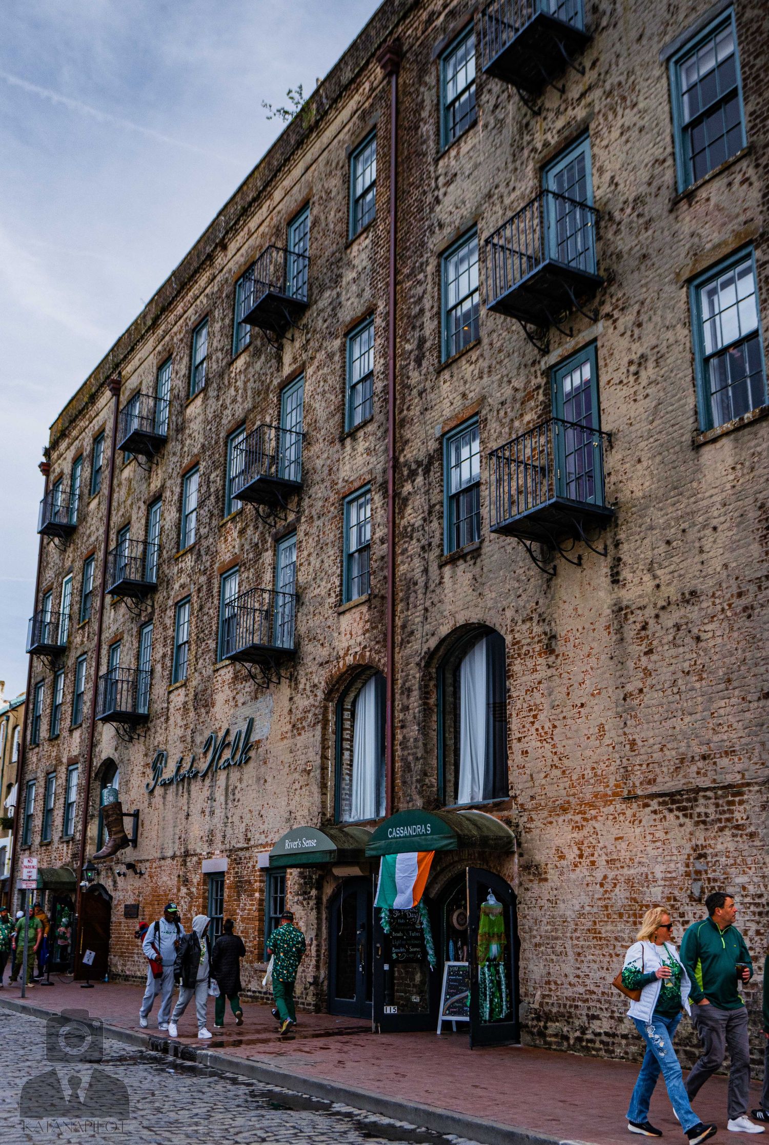 Weathered brick building with multiple balconies and arched doorways on River Street in Savannah.