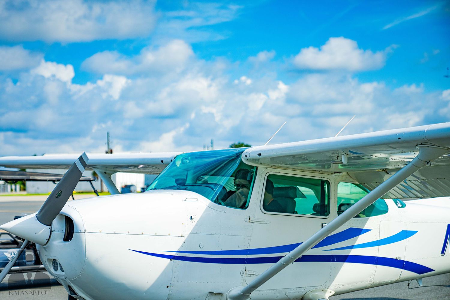 Close-up exterior view of a white Cessna aircraft nose section against blue sky.