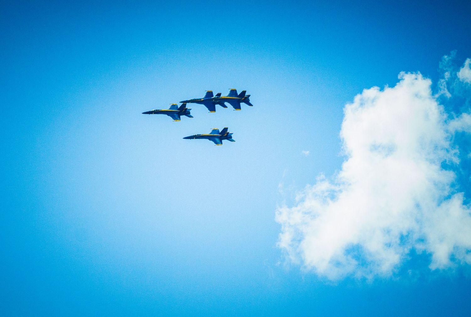 Military aircraft performing aerial maneuvers leaving white vapor trails in blue sky.