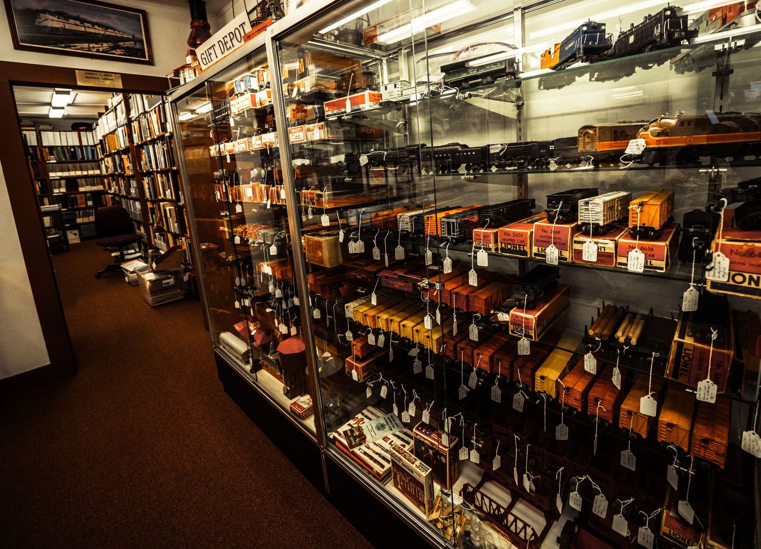 Long view of a model train store showing rows of display cases filled with locomotives and train accessories.