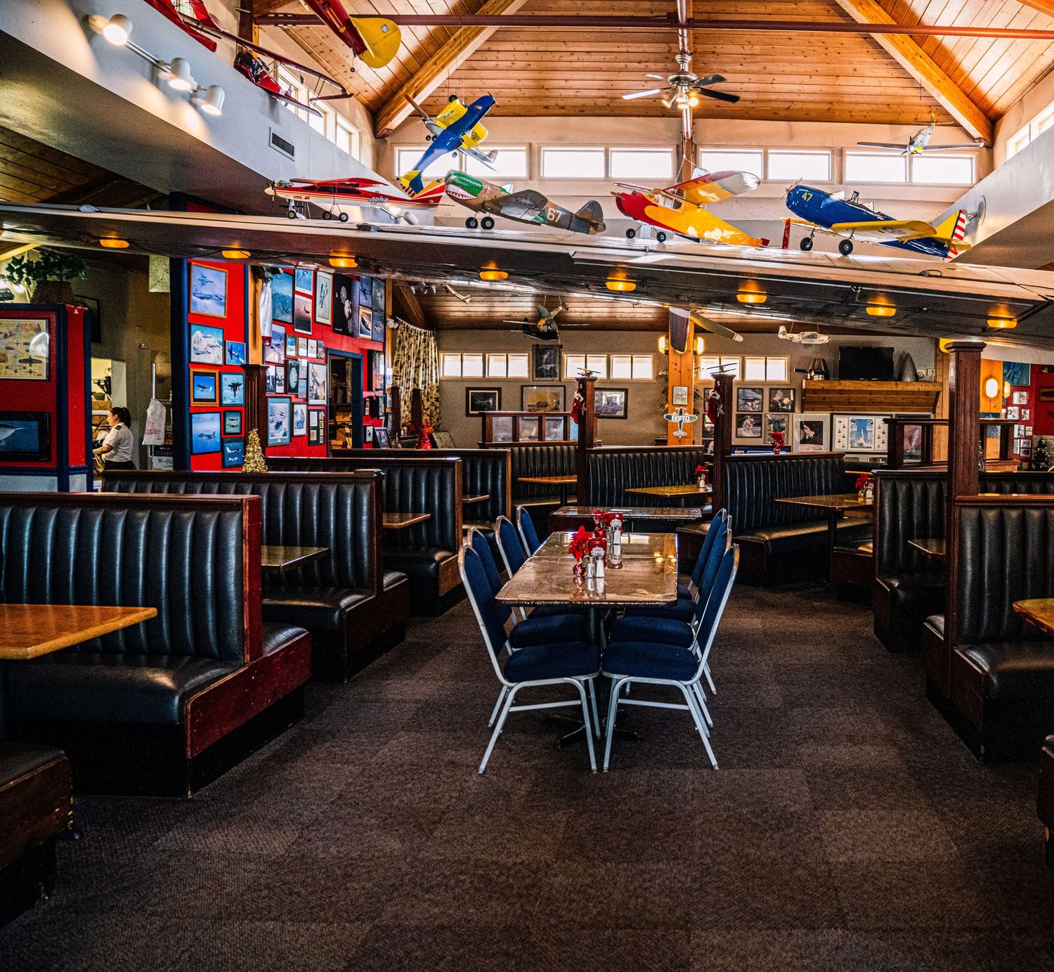 Empty restaurant interior with wooden beams and dark booths showing multiple angles of the dining space.