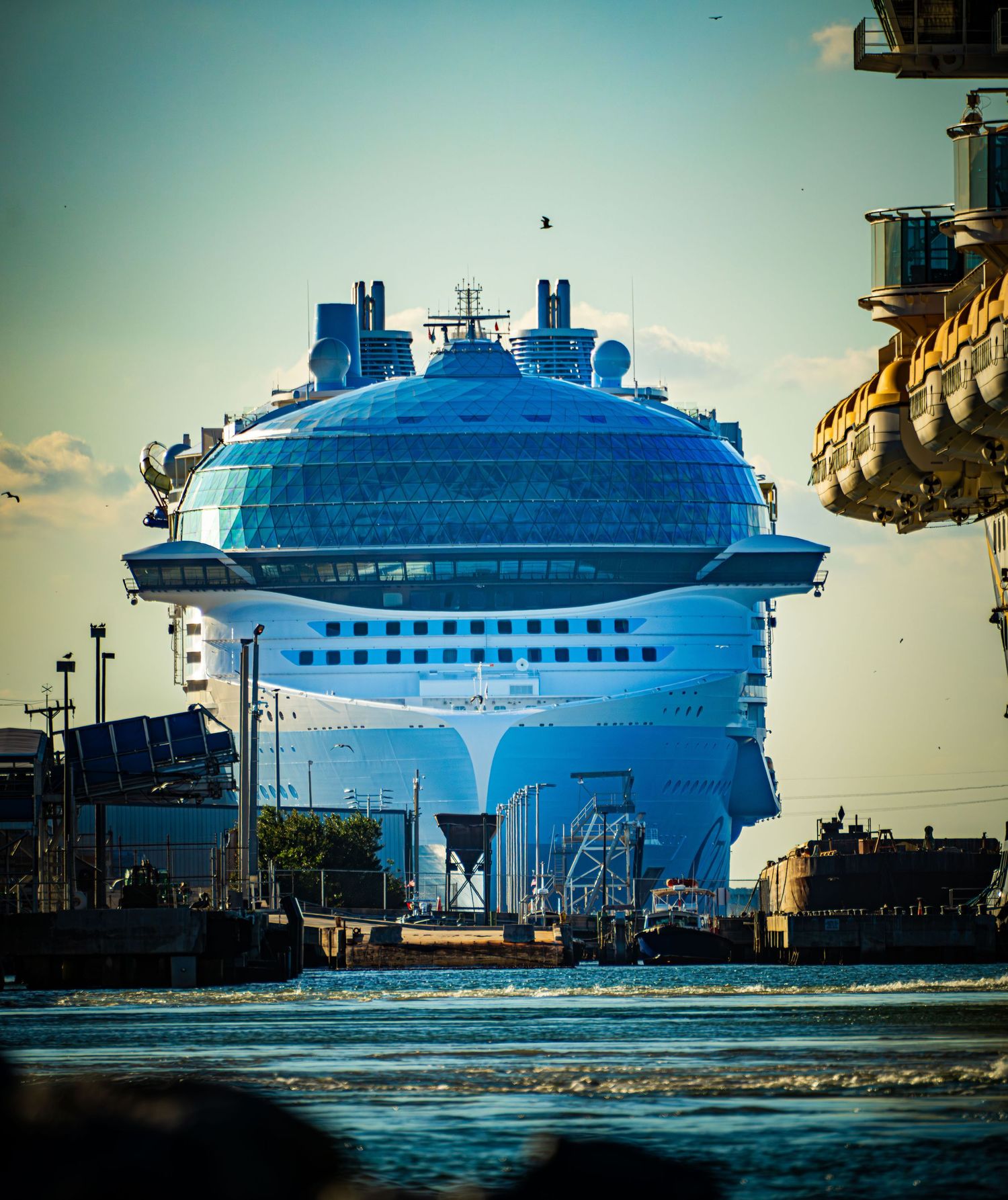 A large blue inflatable dome structure sits in an industrial area against a cloudy sky at sunset.