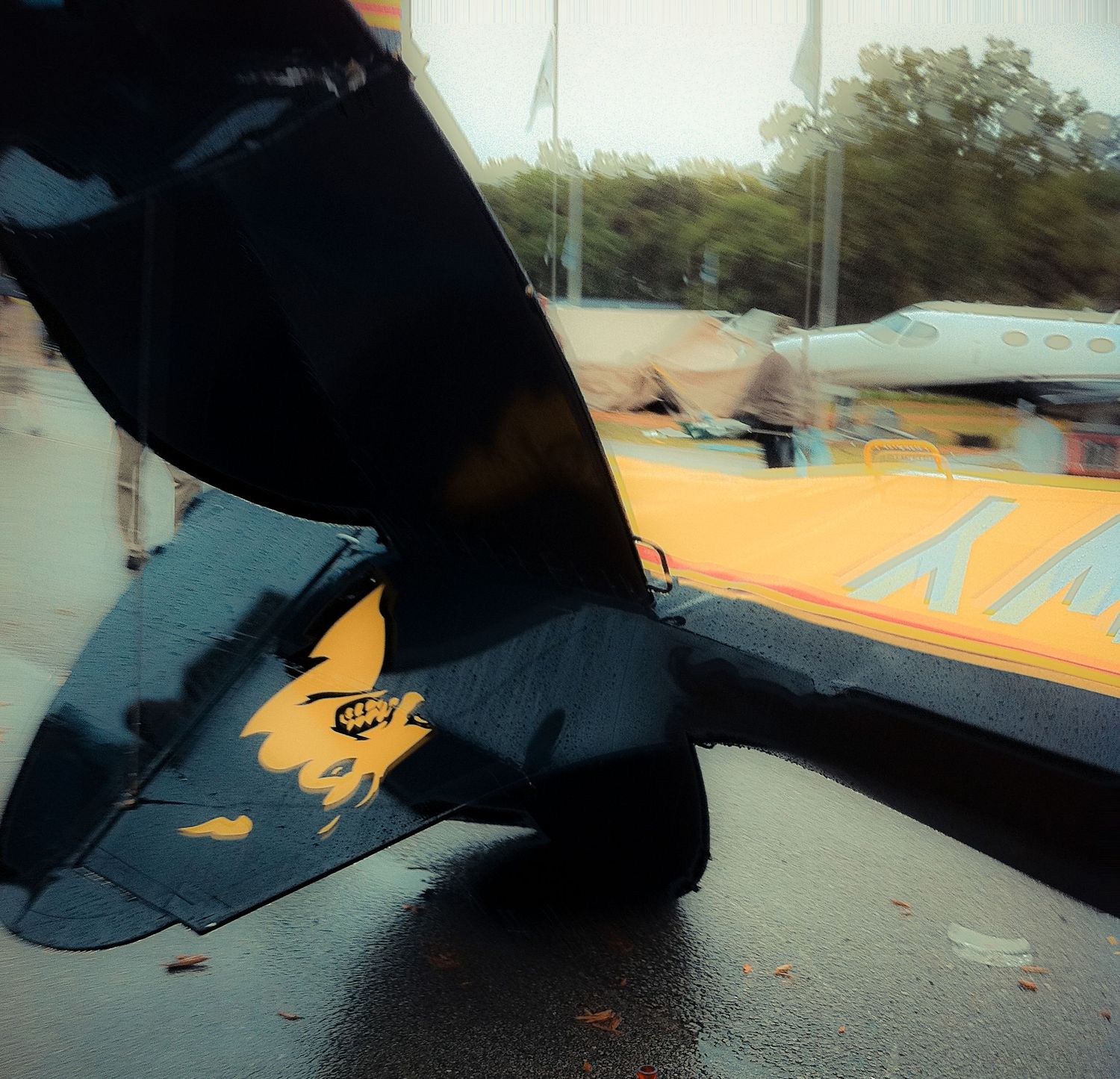 Close-up sequence showing a black umbrella opening against a bright sky with orange tents in the background.