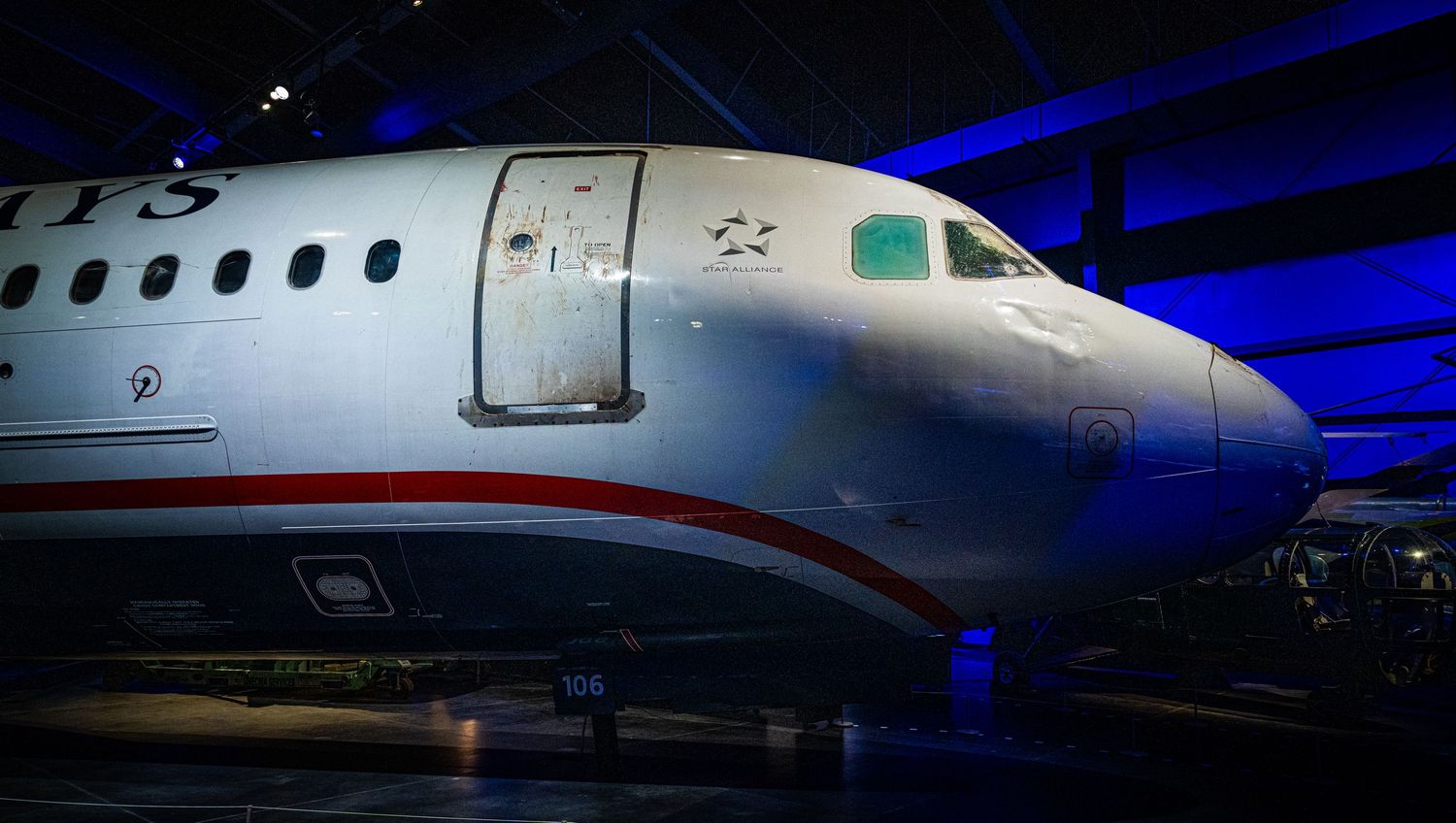 Series of illuminated aircraft nose sections in dramatic blue lighting at aviation museum.