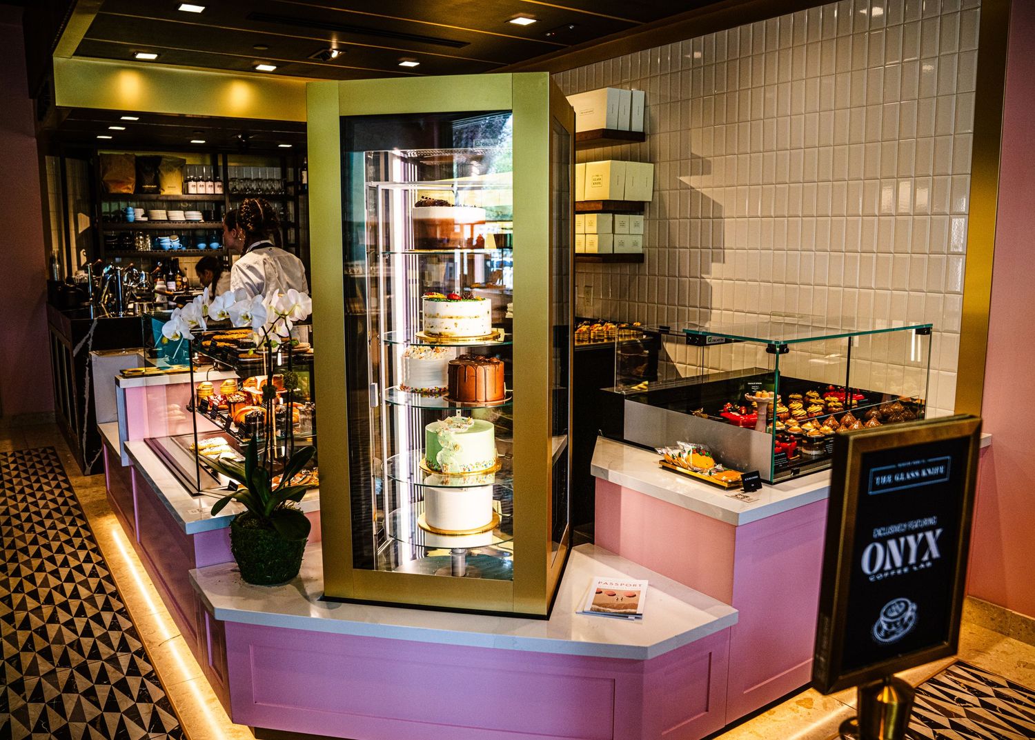 Modern cafe interior with sleek display cases and purple accent lighting showcases pastries and baked goods.