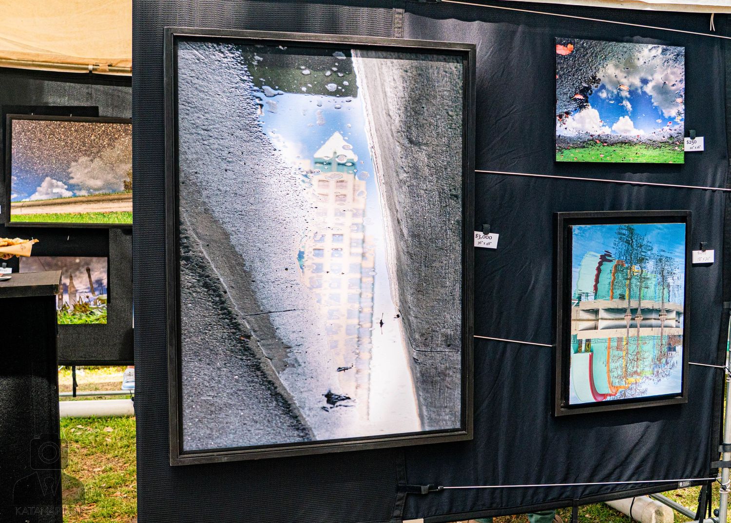 Black display panels showing framed photographs mounted outdoors at an art festival.