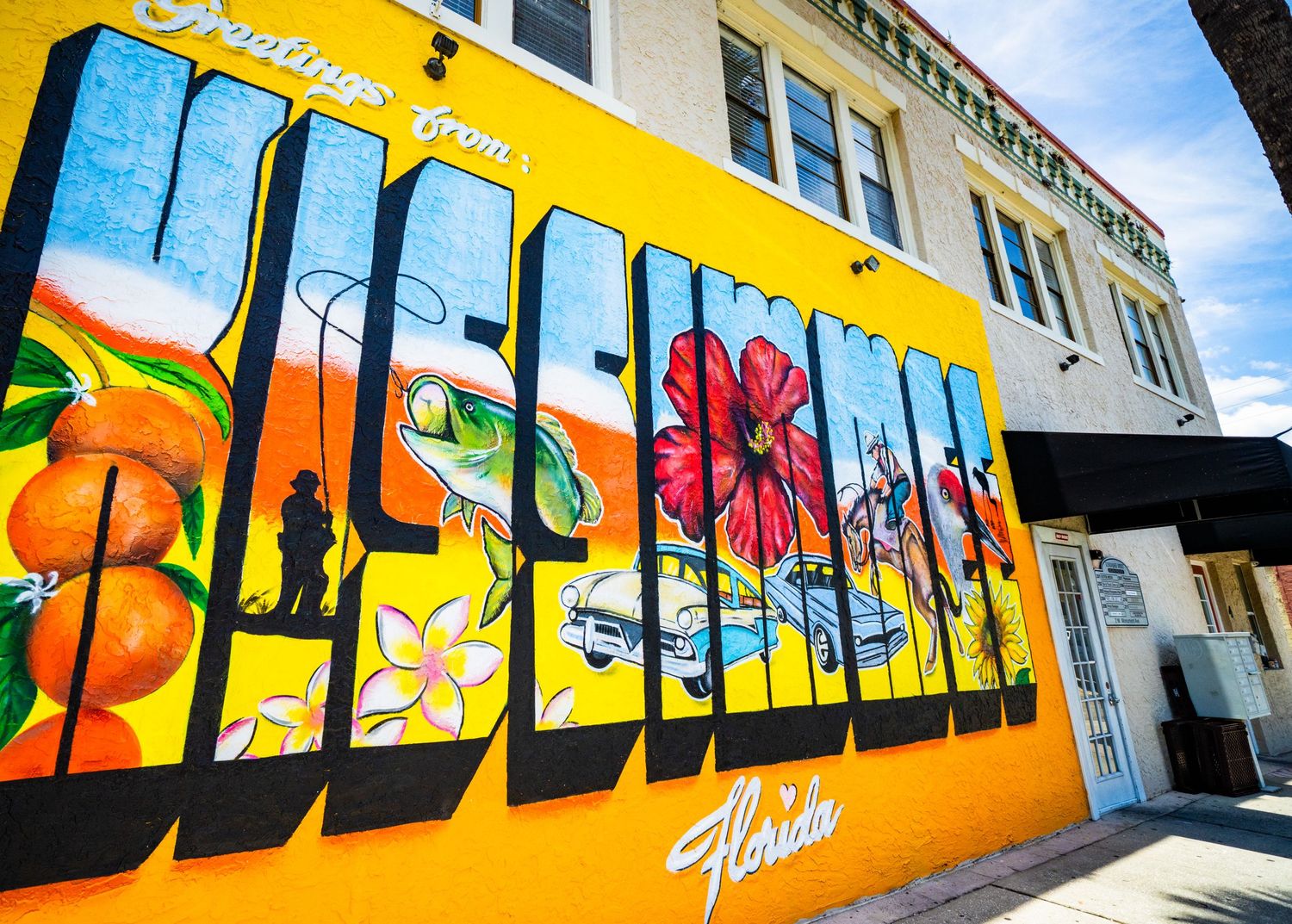 Large yellow wall mural with tropical fruit and floral designs in bright colors.