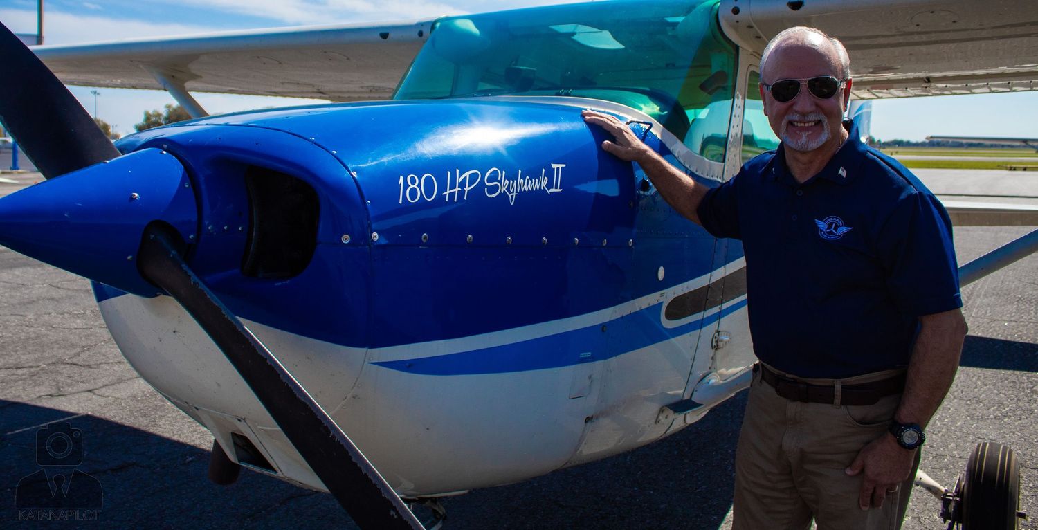 Light aircraft with distinctive blue stripe design parked at airfield.