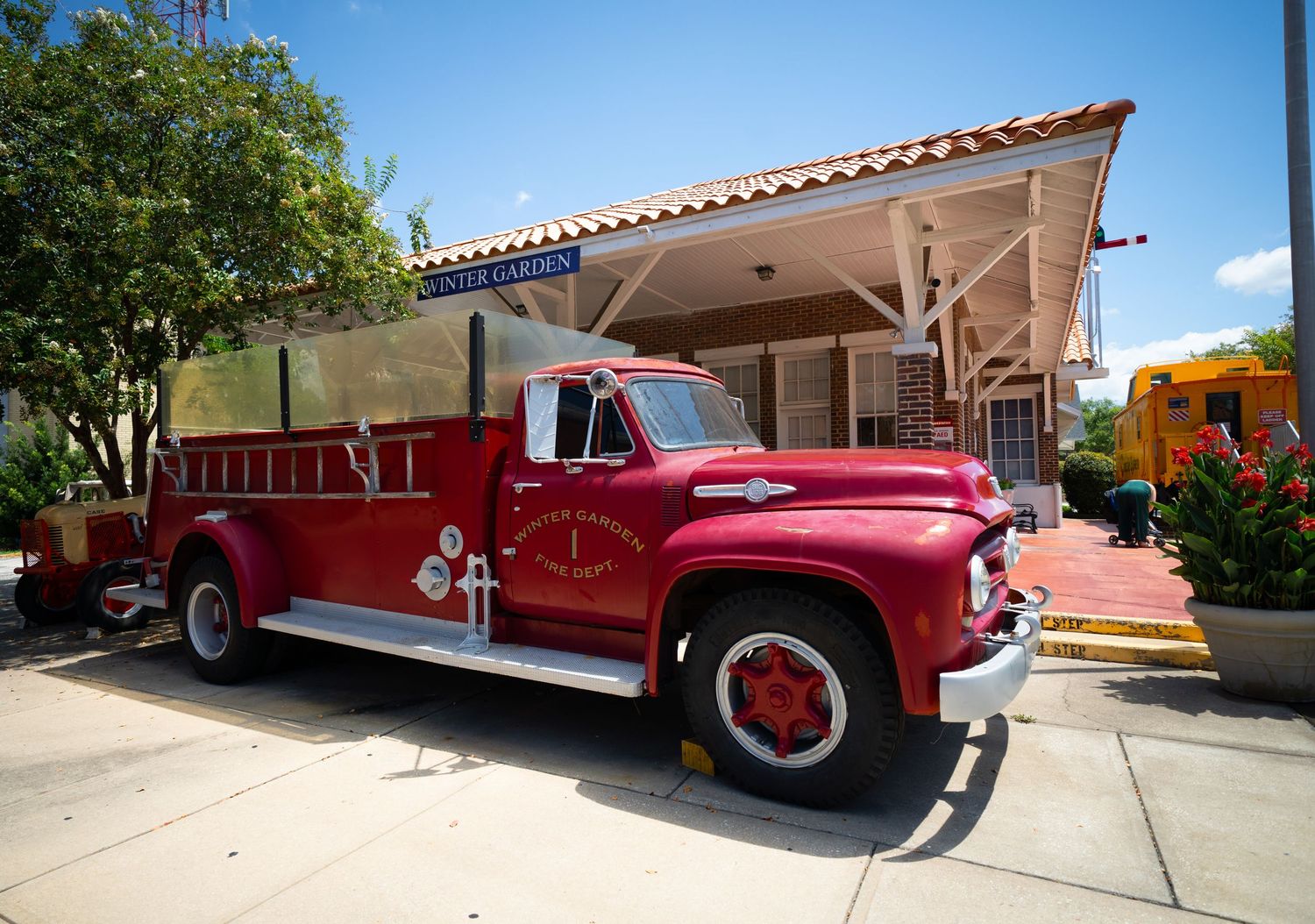 Vintage red fire trucks displayed in a row outside a building on a sunny day.