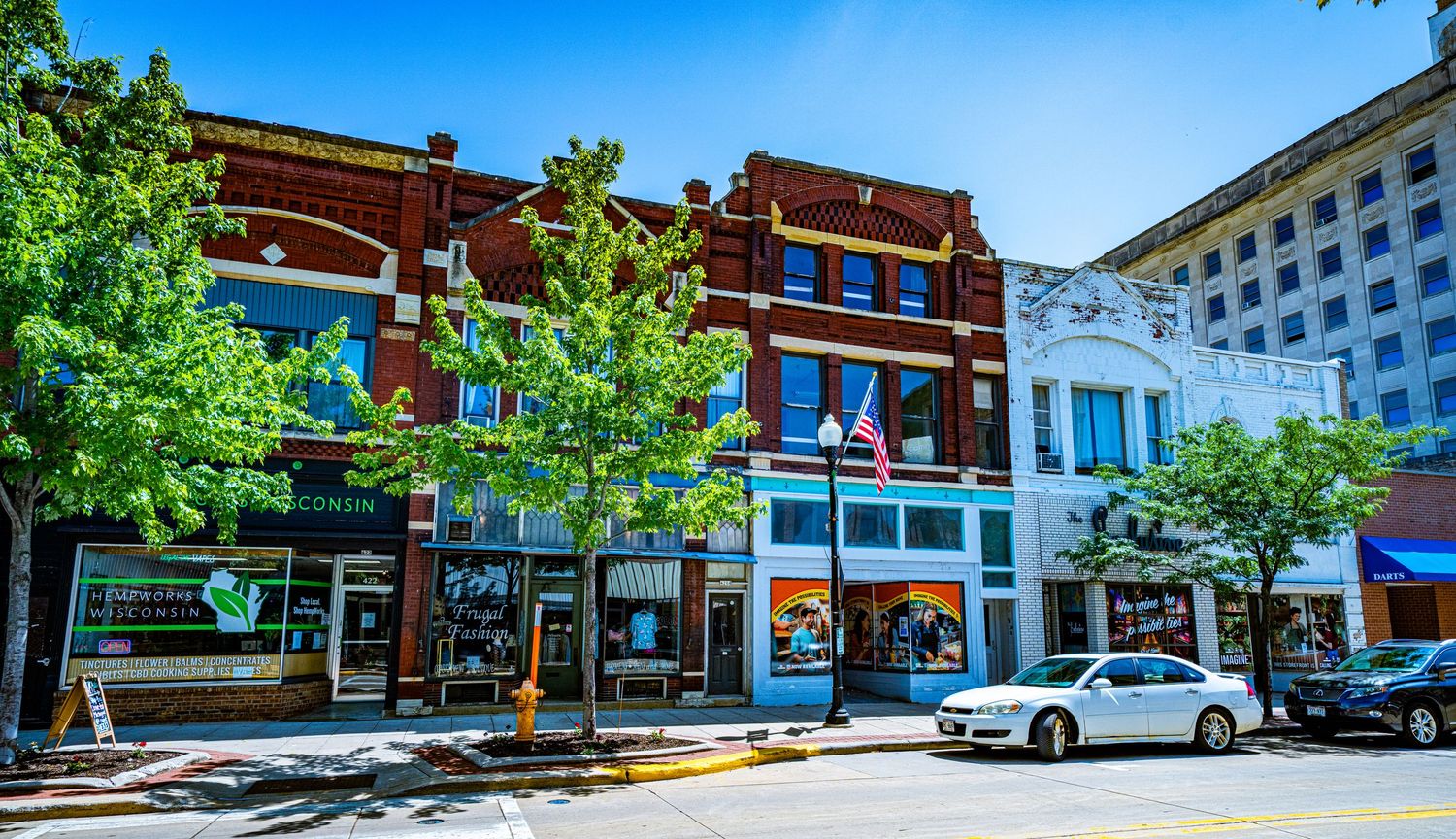 Small town commercial district features brick buildings and storefronts along a quiet street.