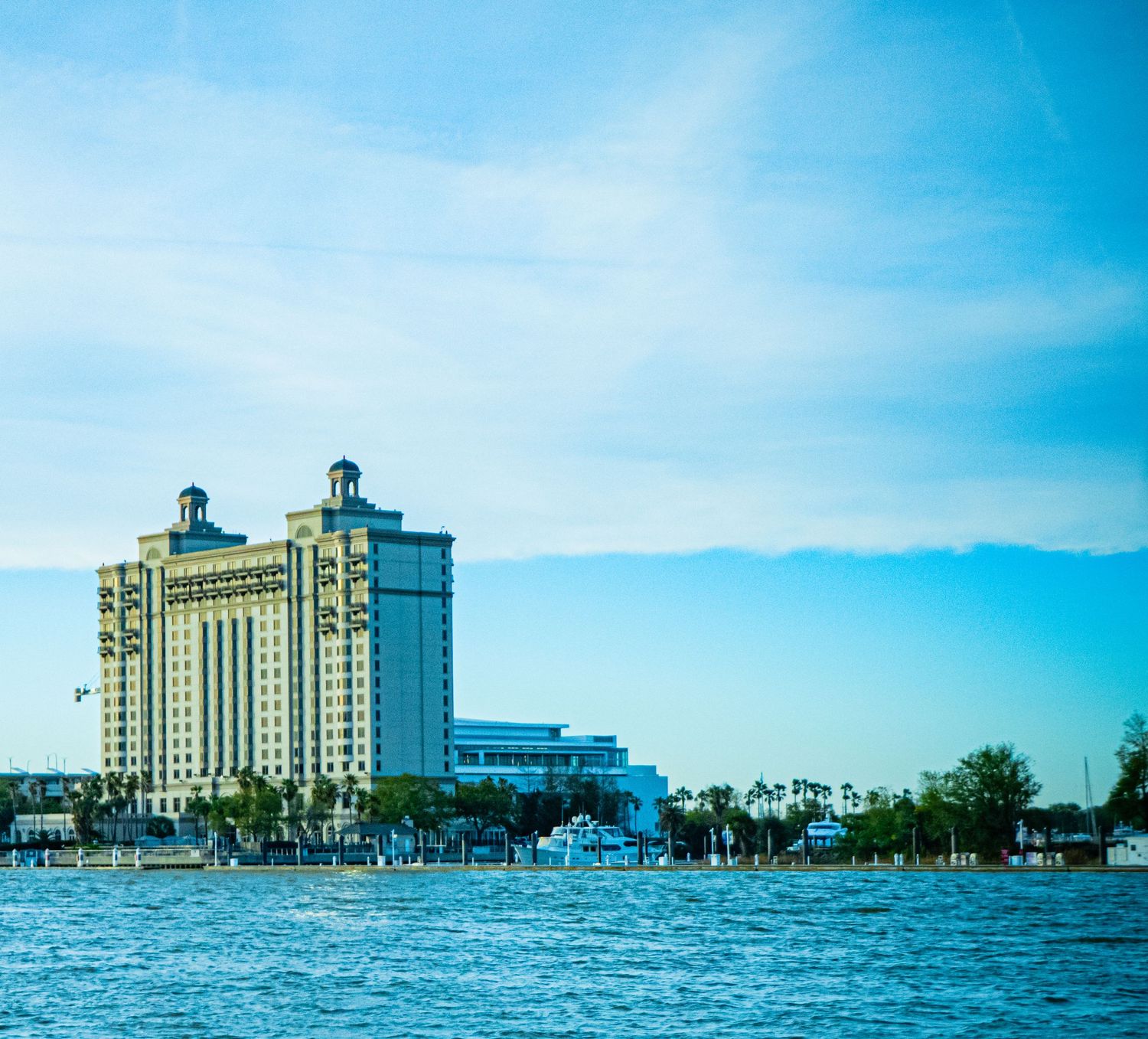 A panoramic view of a beachfront hotel with palm trees and blue waters along the Gulf Coast shoreline.