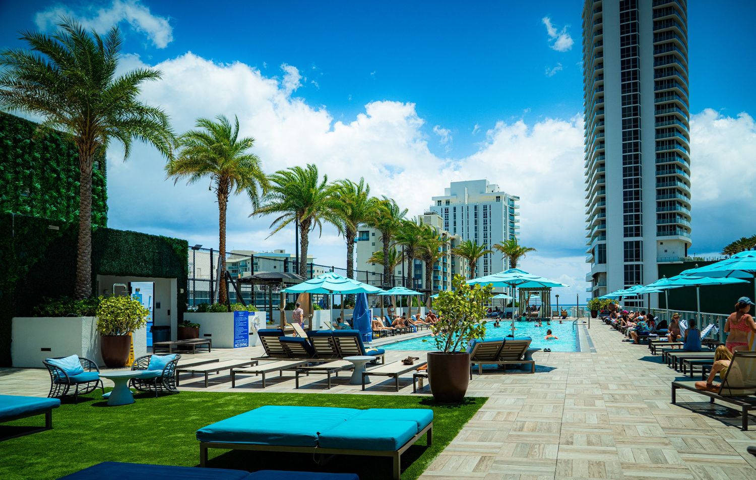 Luxury beachfront pool deck with lounge chairs and palm trees overlooking the ocean.