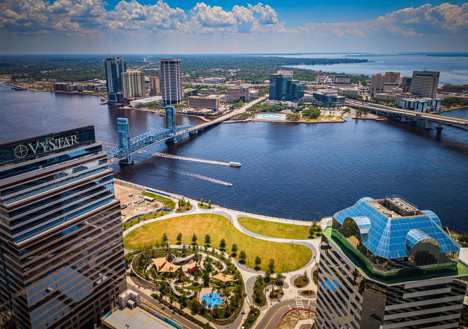Aerial view of Jacksonville, Florida skyline along the St. Johns River with the Main Street Bridge and VyStar tower visible.