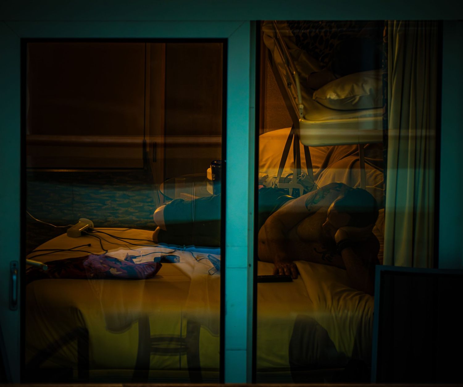 Dark interior view of an empty hotel room with soft ambient lighting filtering through windows.