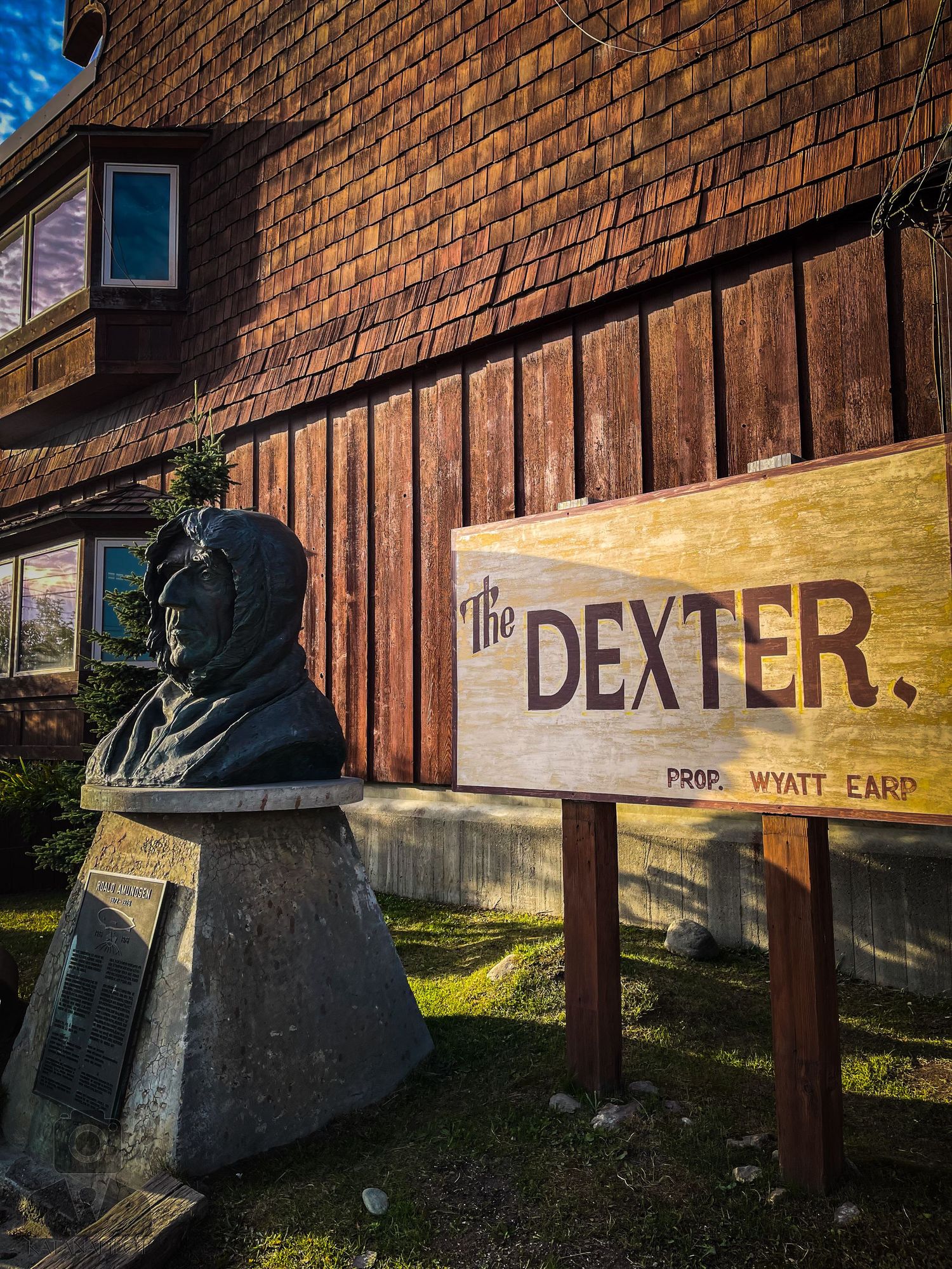 Rustic wooden sign reading 'The Dexter' mounted on a brick wall.