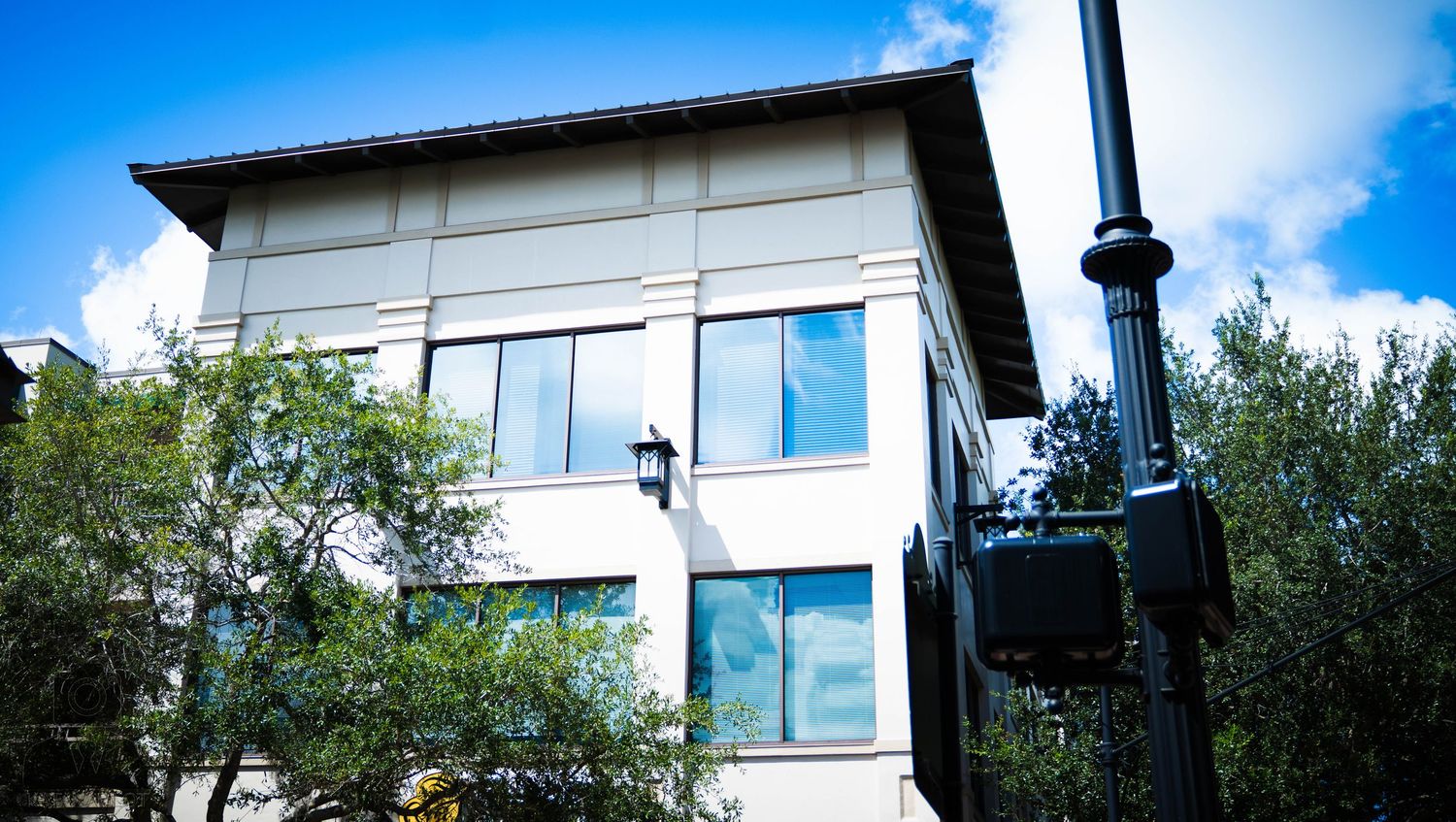 Modern white building exterior with large windows and blue sky in the background.