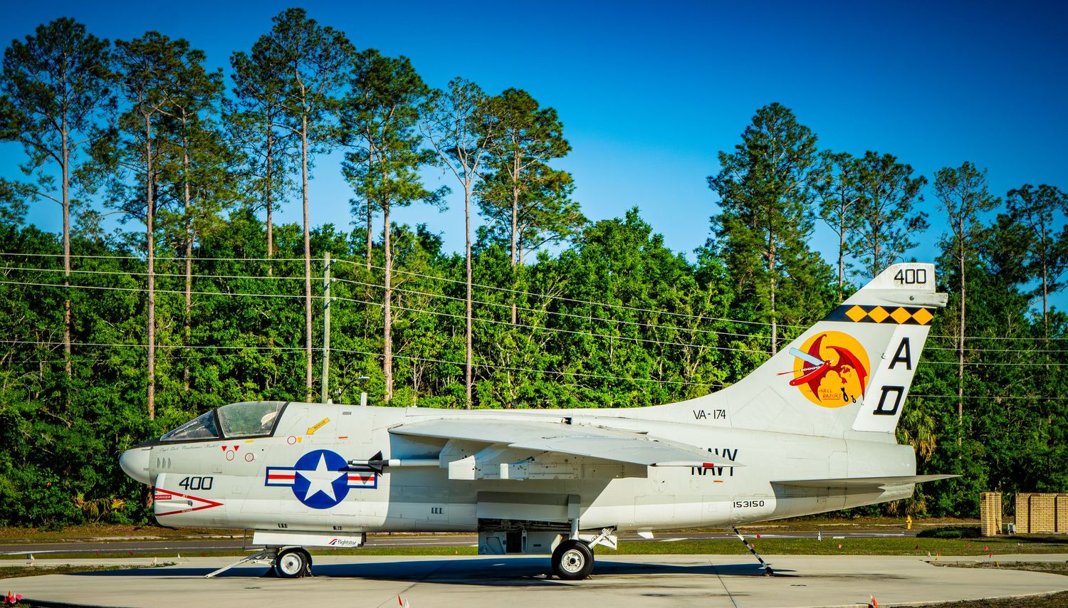 Vintage U.S. Navy S-2 Tracker aircraft on display outdoors with colorful squadron markings and lush green trees behind.
