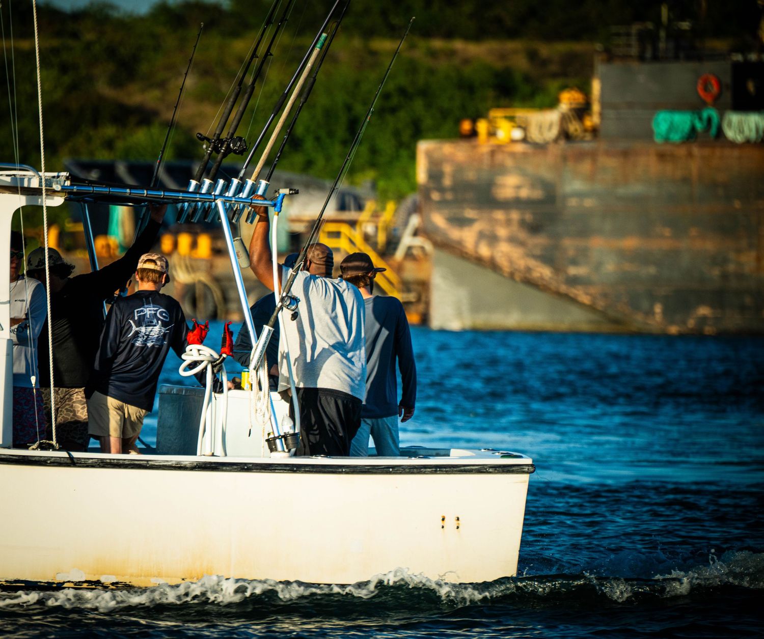 Fishing boats float on calm blue waters near the shoreline during a sunny day.