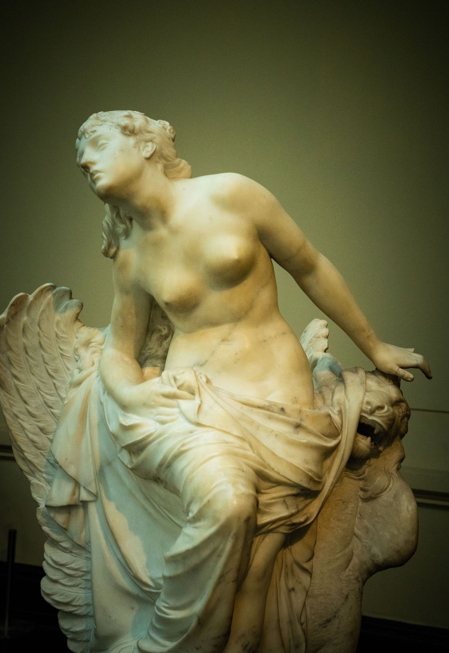 Classical marble sculpture of winged figure in dramatic lighting.