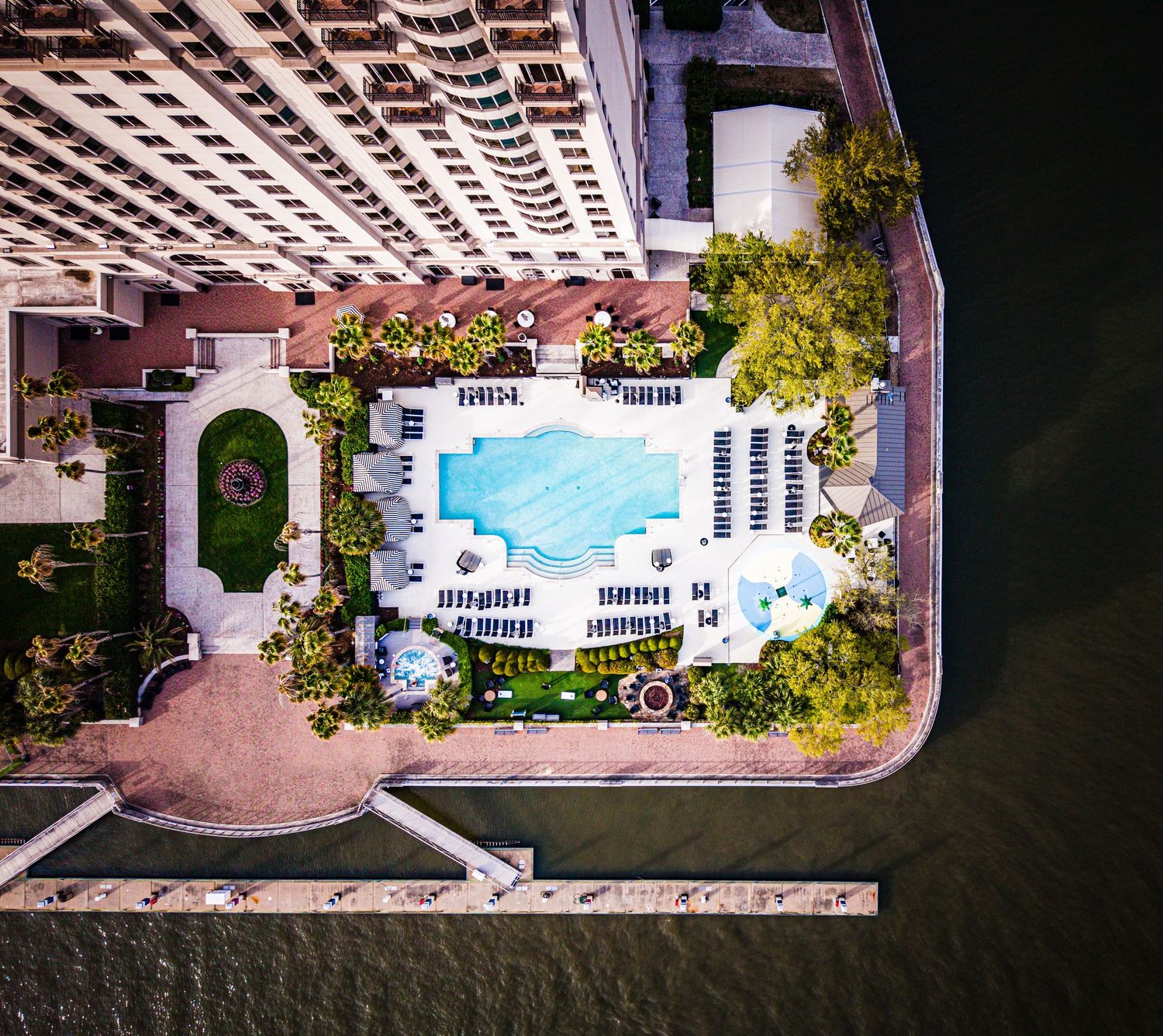 Aerial view of luxury waterfront condominiums with swimming pools and boat docks along the coastline.