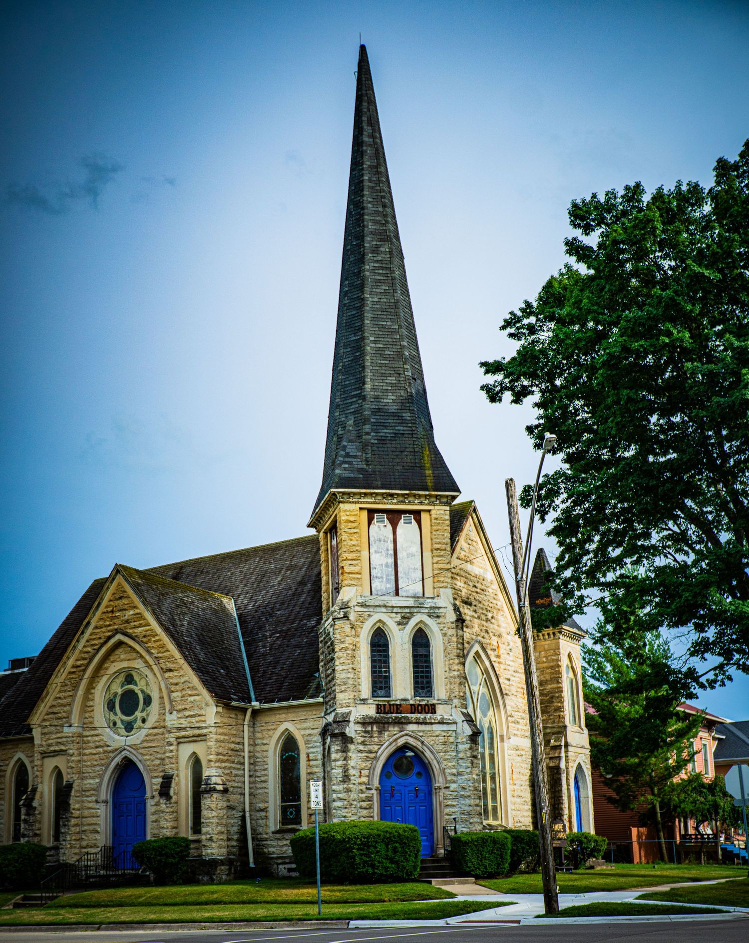 Gothic stone church with tall spire and blue doors photographed from multiple angles.