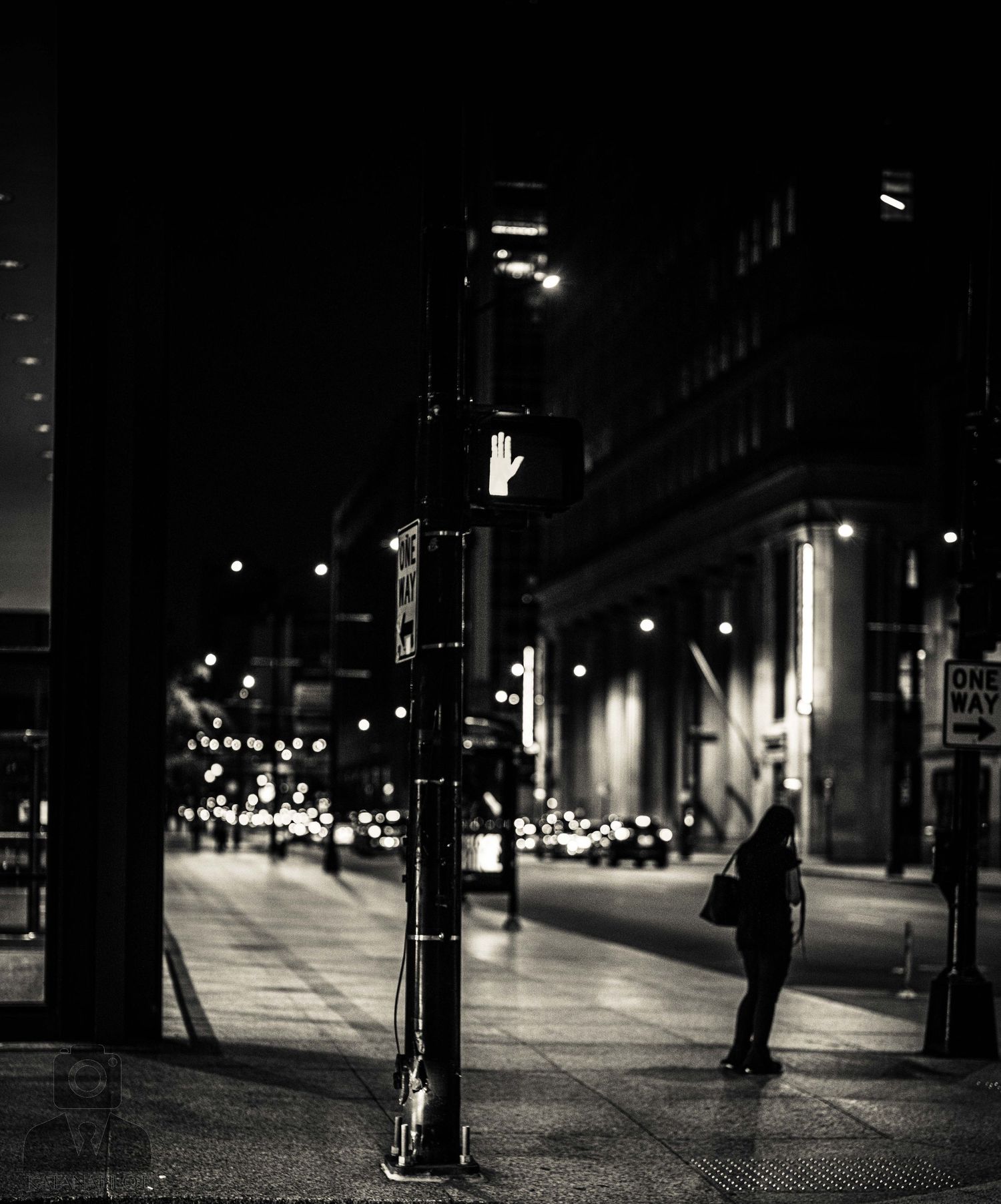 Empty city sidewalk at night with street lights creating dramatic shadows.