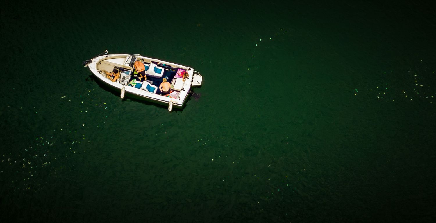 Aerial view of small boats floating on dark green water in a marina.