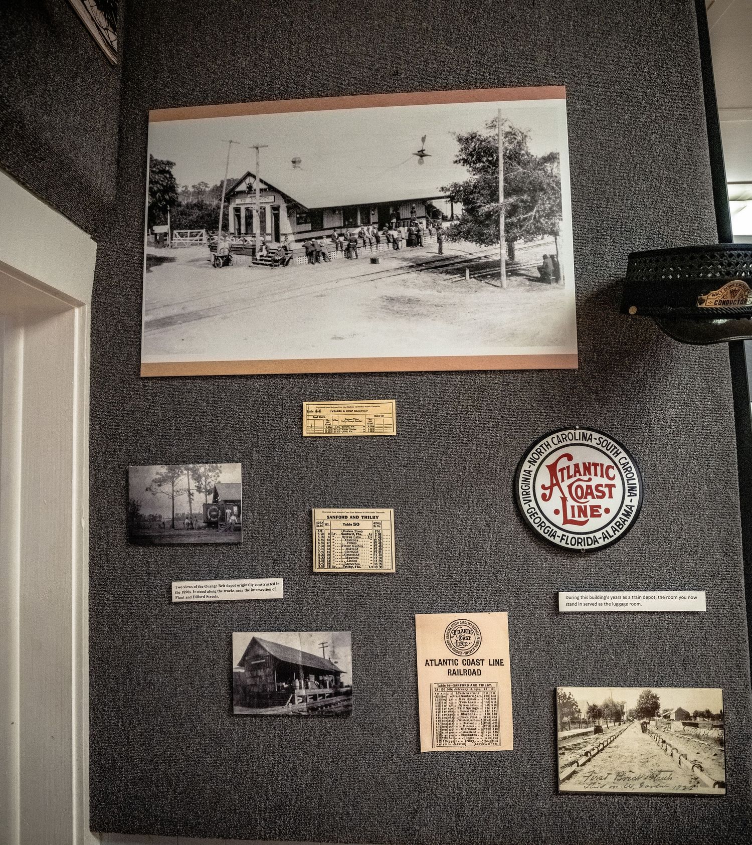 Historic photographs and memorabilia mounted on gray walls in a museum gallery.
