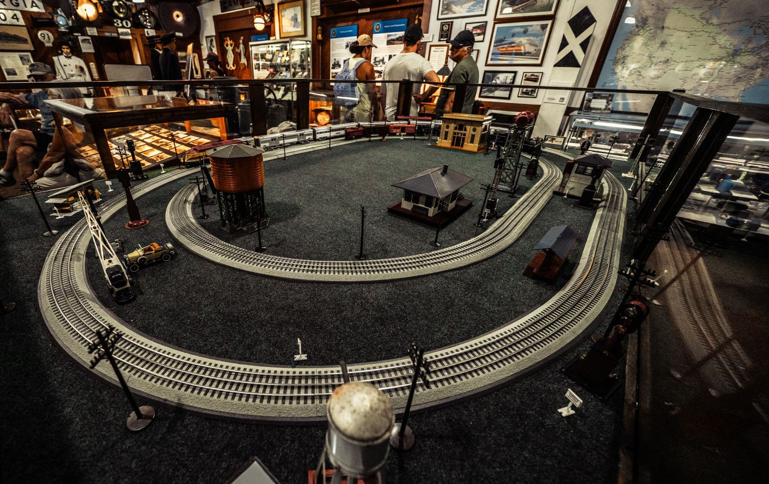 Model railroad setup featuring multiple track levels and detailed landscape elements in a dimly lit room.