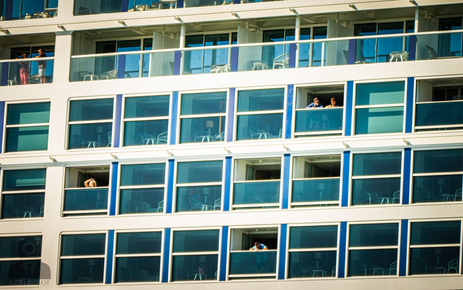Modern cruise ship exterior showing multiple decks of private balconies and reflective windows.