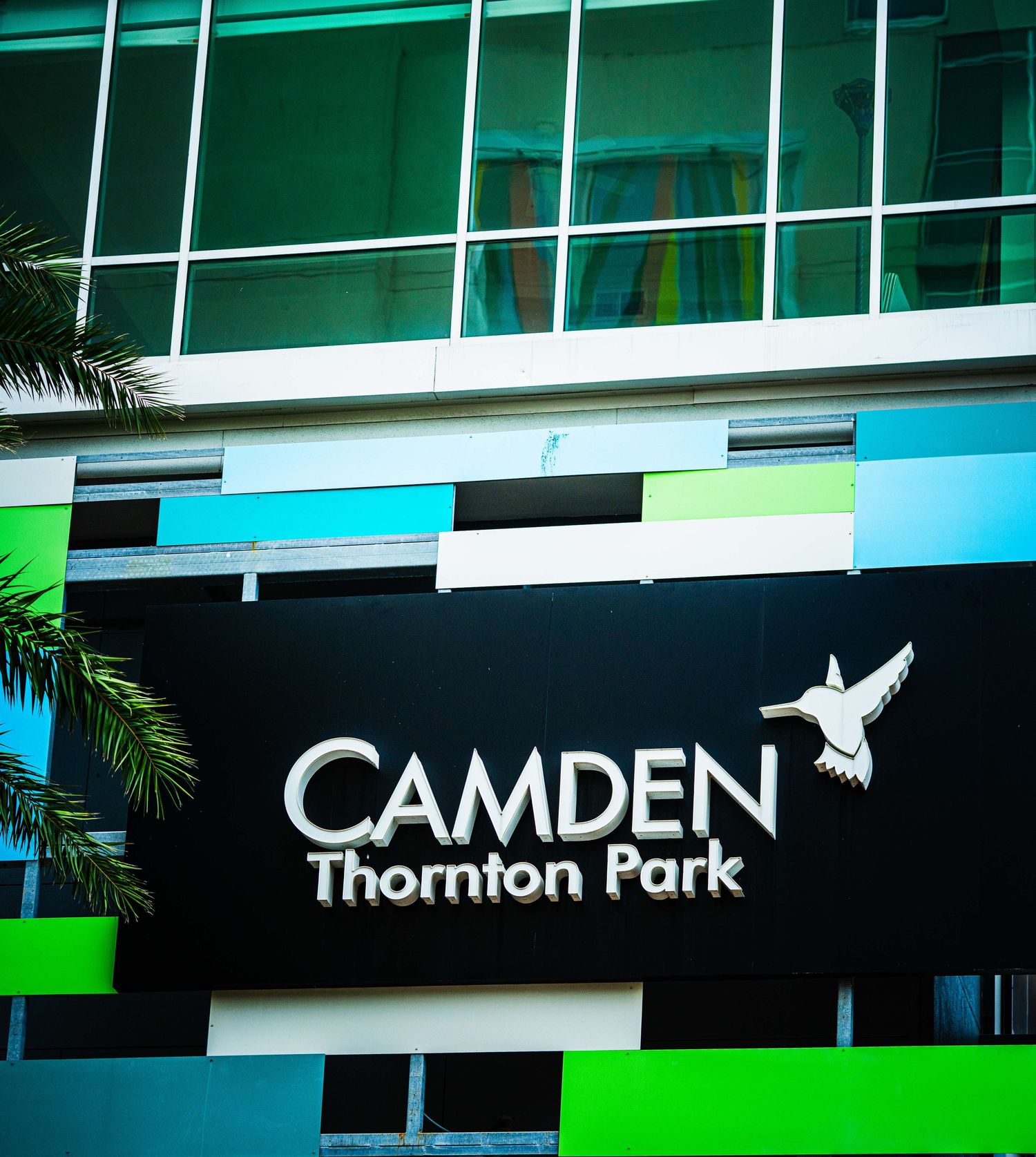 Camden Thornton Park apartment complex sign with hummingbird logo on modern building facade with colorful accents.