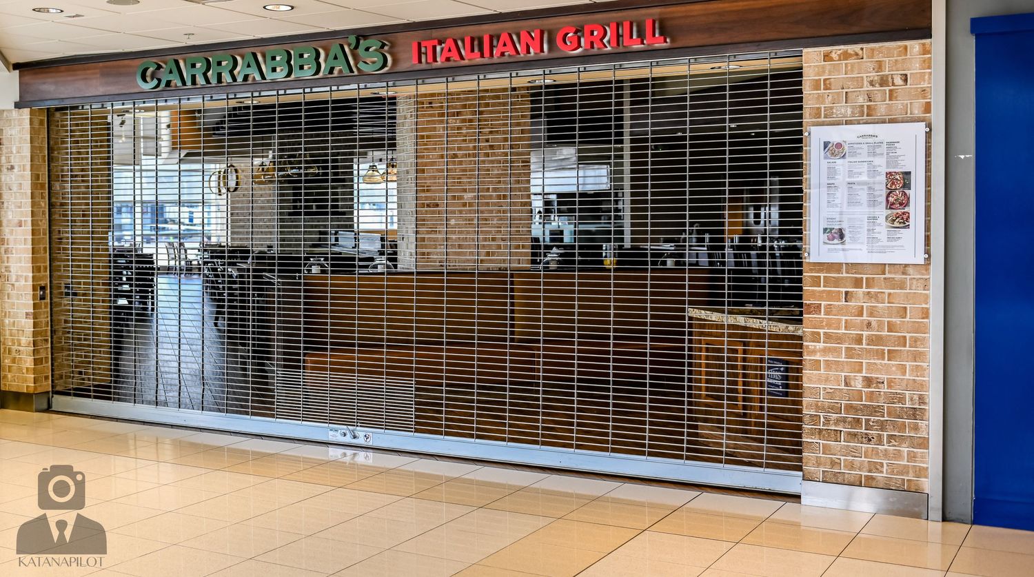 Mall interior showing Carnation Cafe storefront with security gates and brick accent walls.