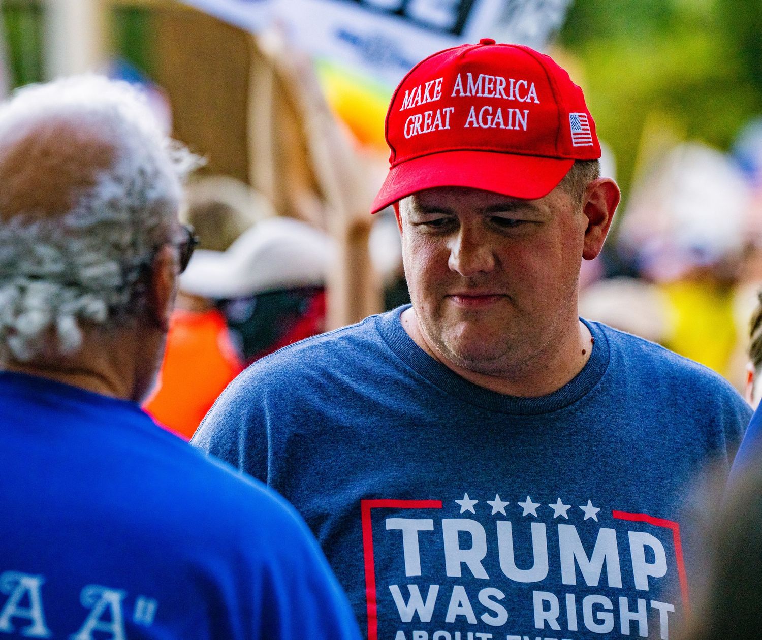 Political supporter wearing campaign merchandise at outdoor gathering.