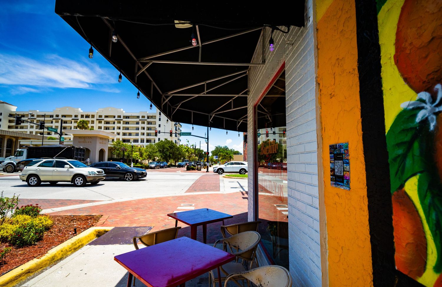 Outdoor seating area with colorful umbrellas and tables along building exterior.