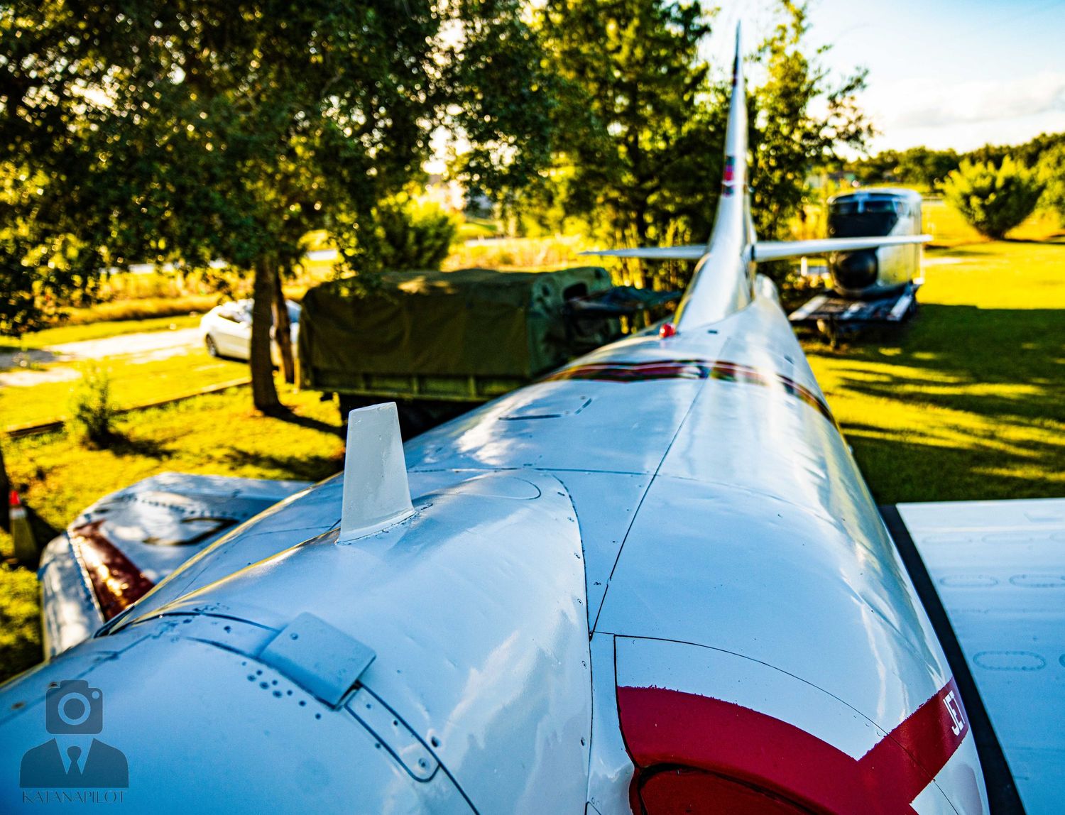 Detailed view of vintage military aircraft fuselage with red and white markings in afternoon sunlight.