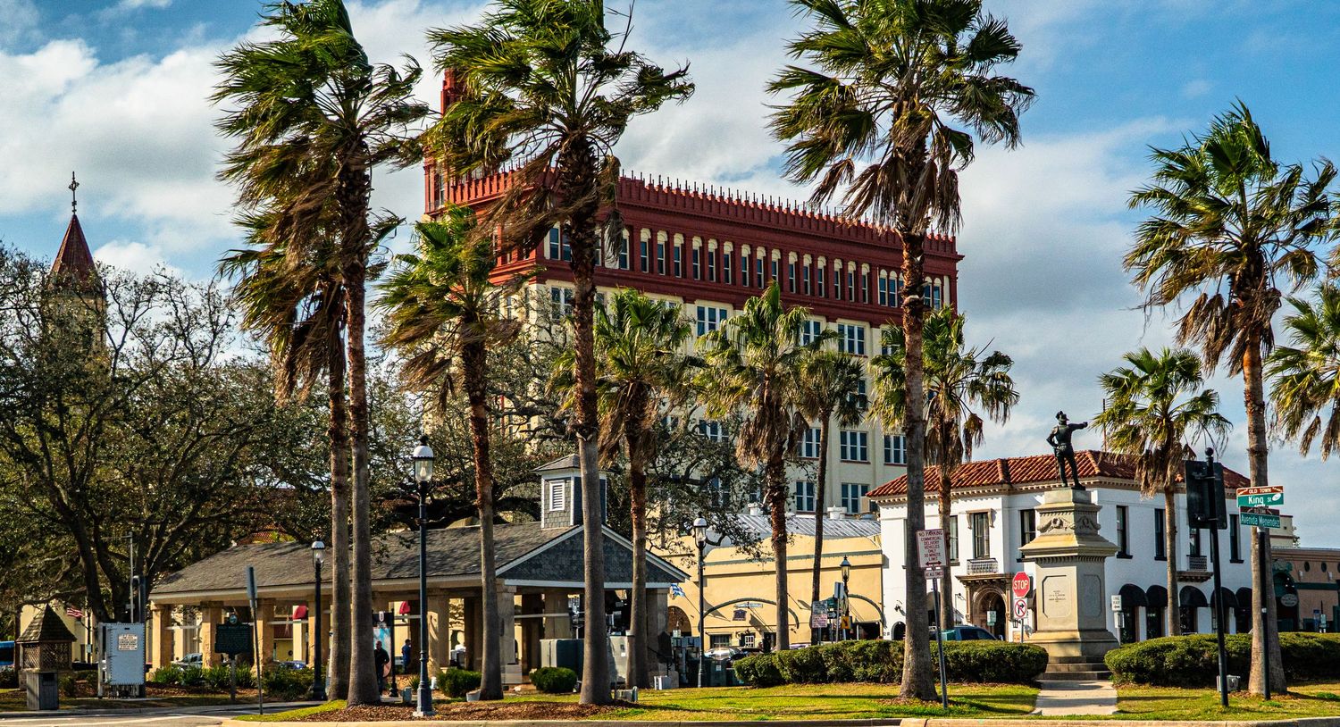 Palm tree lined street with historic Spanish colonial architecture and street lamps.
