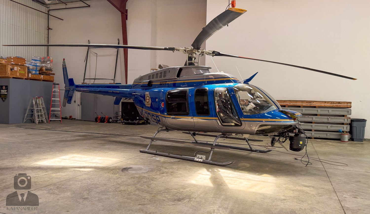 Multiple helicopters parked inside a large aircraft maintenance hangar.