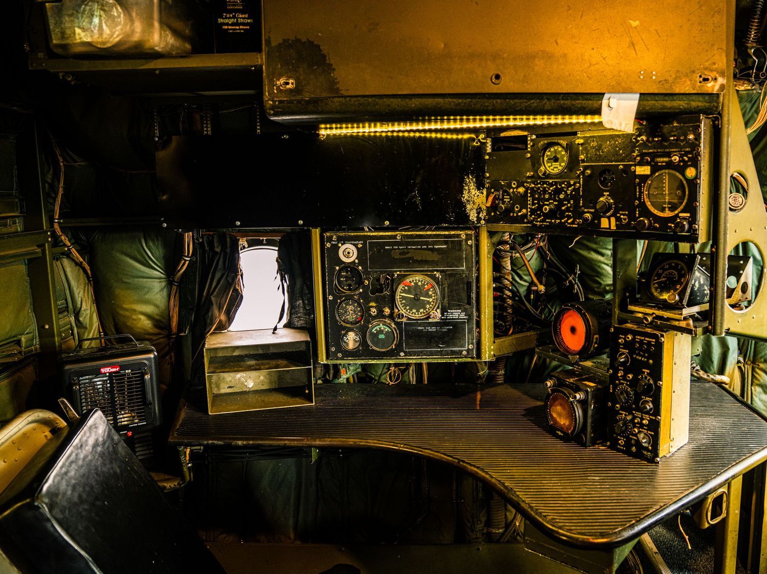 Dark industrial control room with vintage machinery and equipment illuminated by warm lighting.