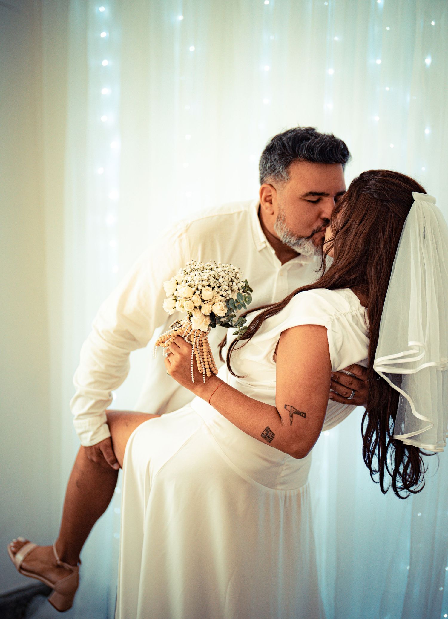 A romantic wedding couple embraces in a series of intimate poses against a backdrop of twinkling lights.