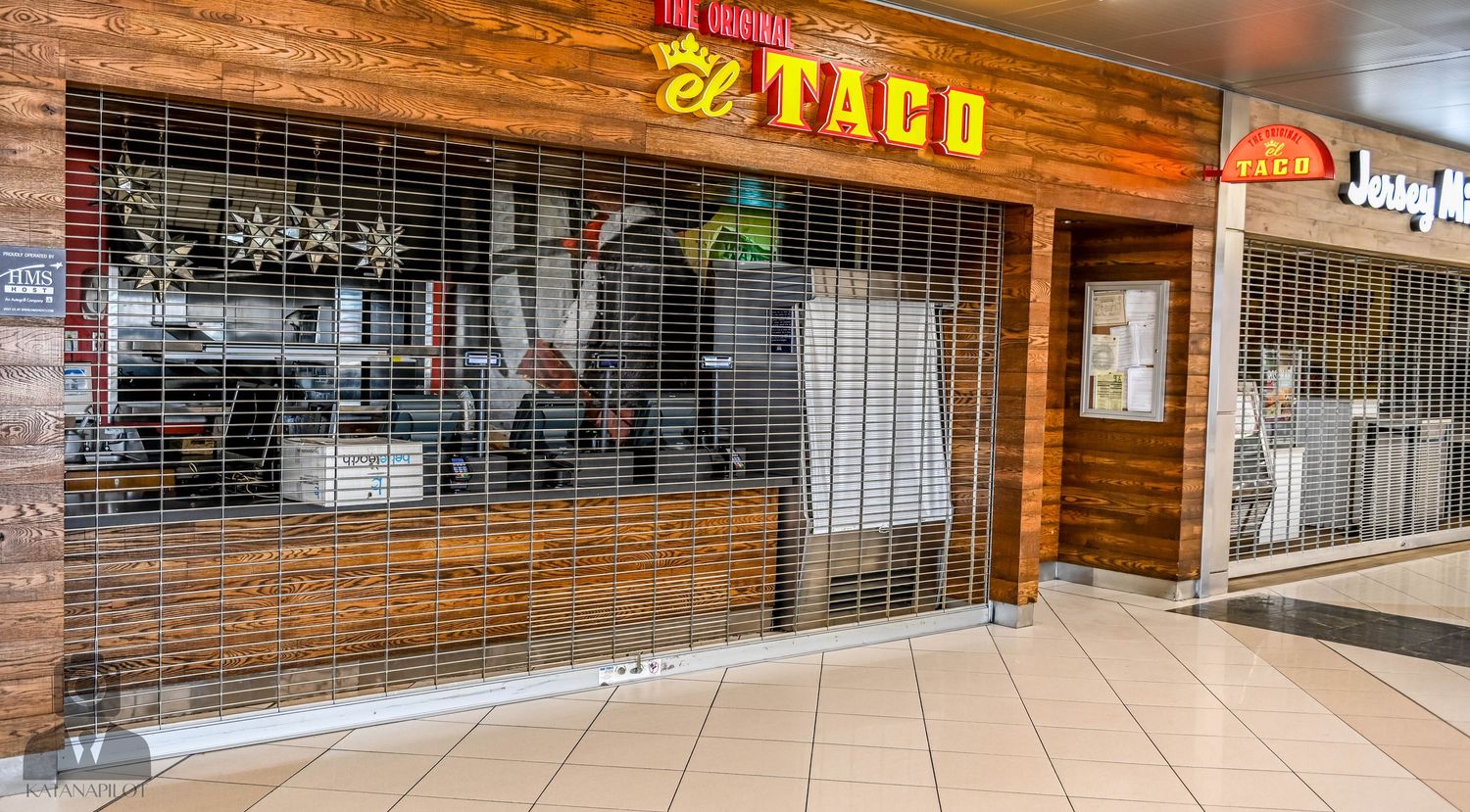 El Taco restaurant with wooden facade and rolled down security gate in mall corridor.