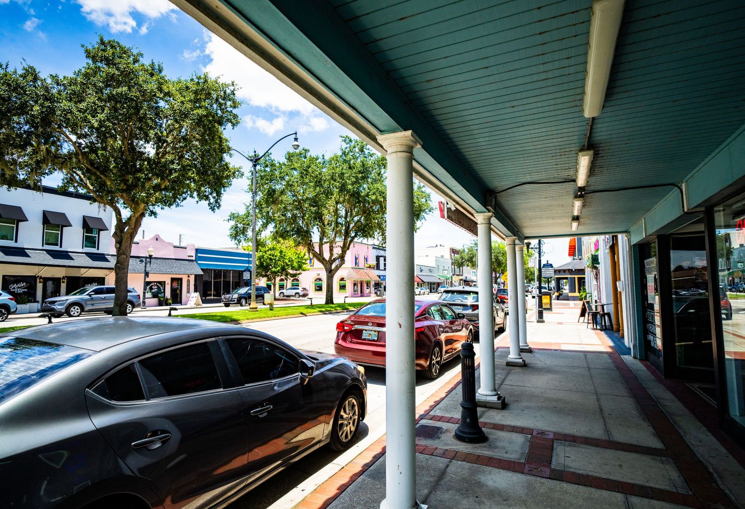 Covered walkway perspective with columns and storefronts in downtown setting.