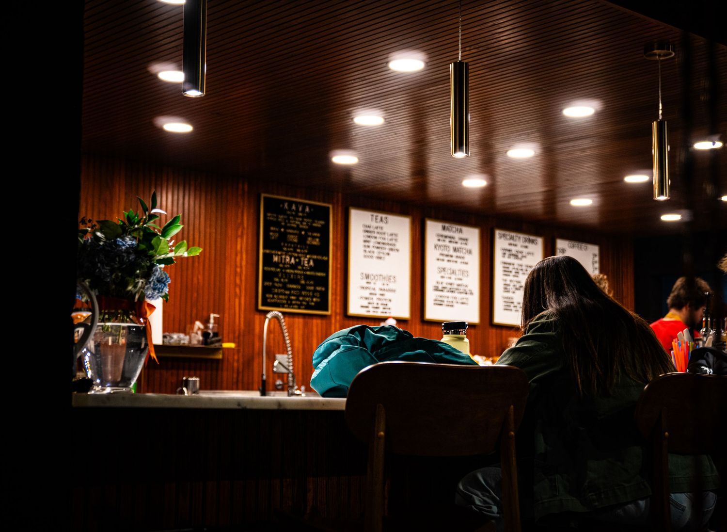 A dimly lit bar interior with wood paneling and hanging pendant lights creates a cozy atmosphere.